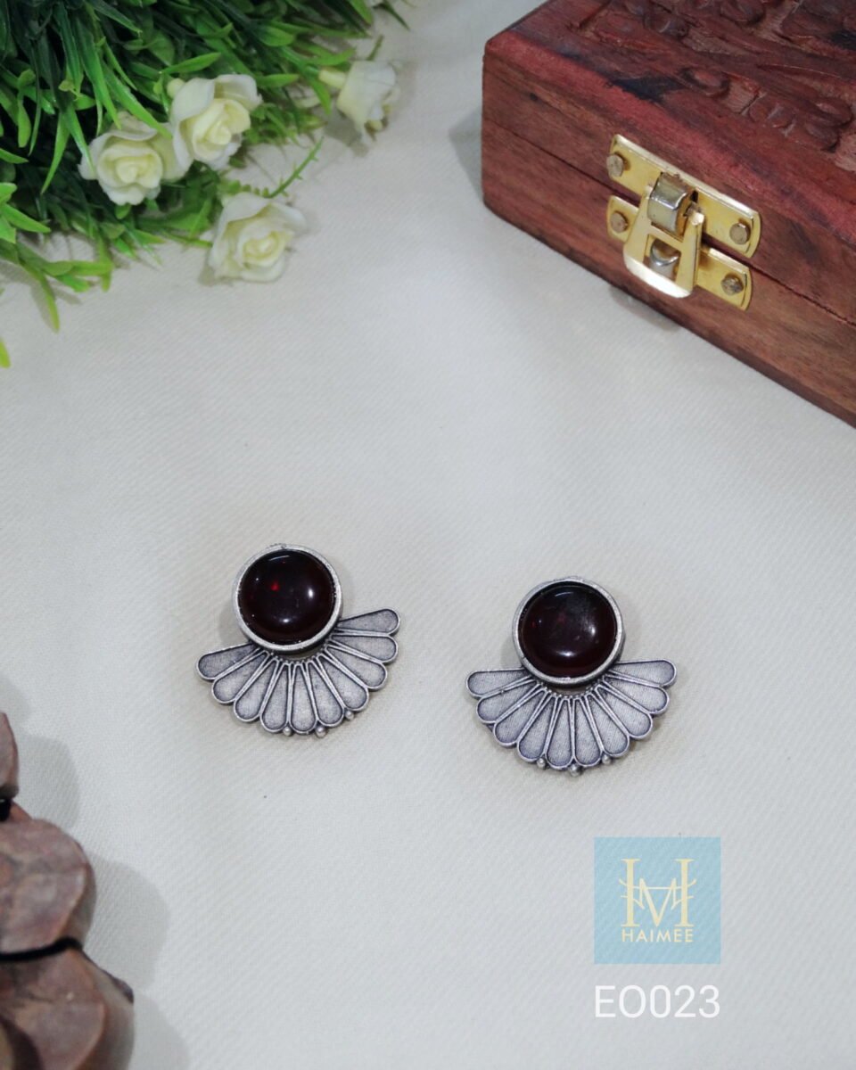 Fan-shaped oxidized silver stud with stone on display, showcasing modern Indian tribal jewellery design.