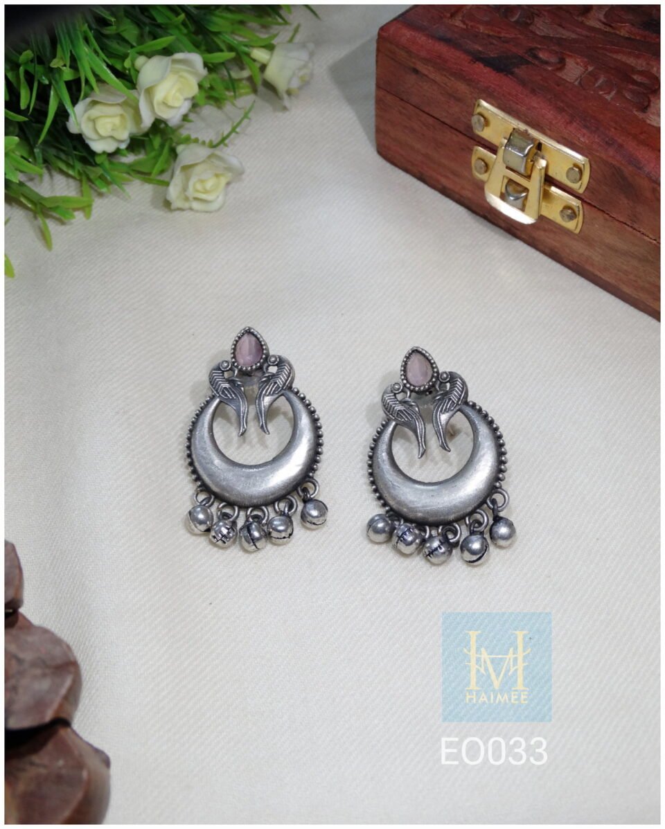 Silver crescent moon-shaped tribal earrings with intricate detailing, presented on a product page for tribal jewellery online India.