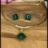 Elegant Husli necklace and earrings set. Features a gold-plated brass design, square emerald green Monalisa stones, and a unique pendant. Shop now!