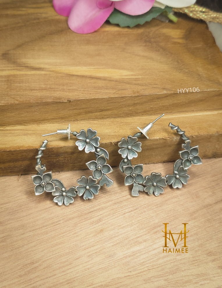 Classy floral design silver design earrings made from brass placed on a wooden surface