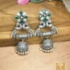 silver oxydized jhumka of brass with pearl motifs and green stones