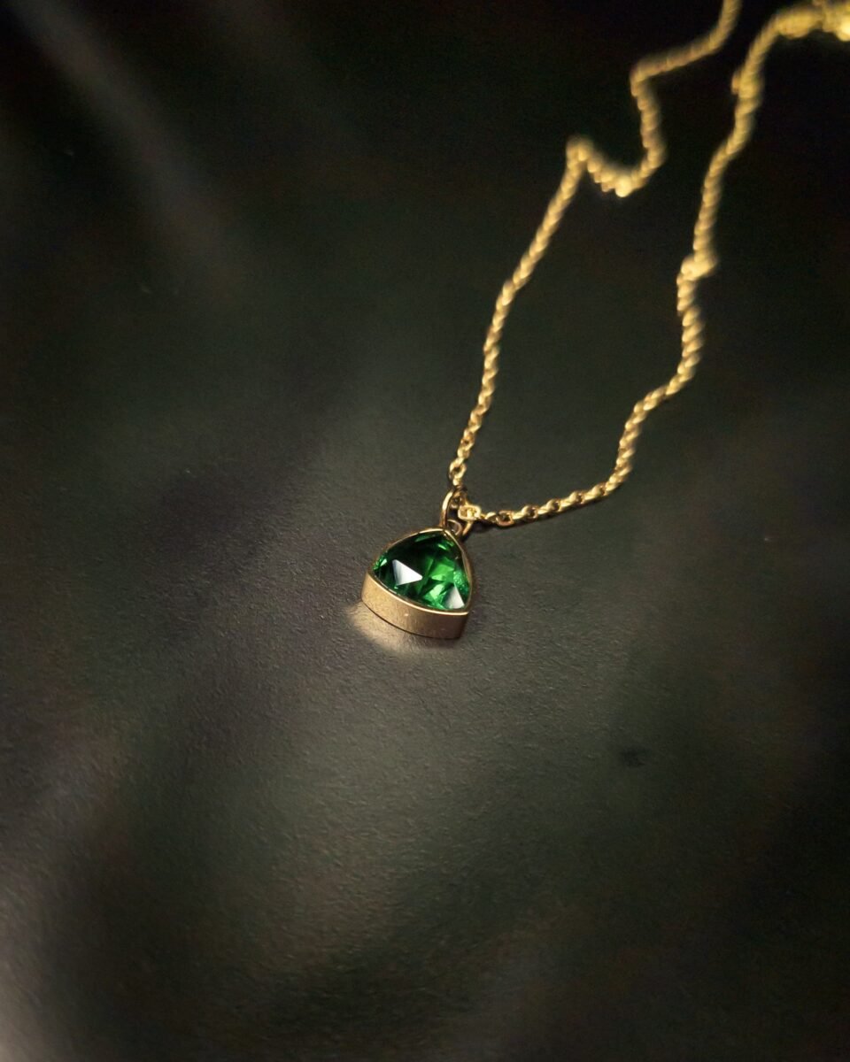 Elevate your everyday look with this polished anti tarnish, gold plated bezel green crystal triangle pendant necklace. The hypoallergenic, water resistant properties ensure both style and comfort. Shop now at Haimee.